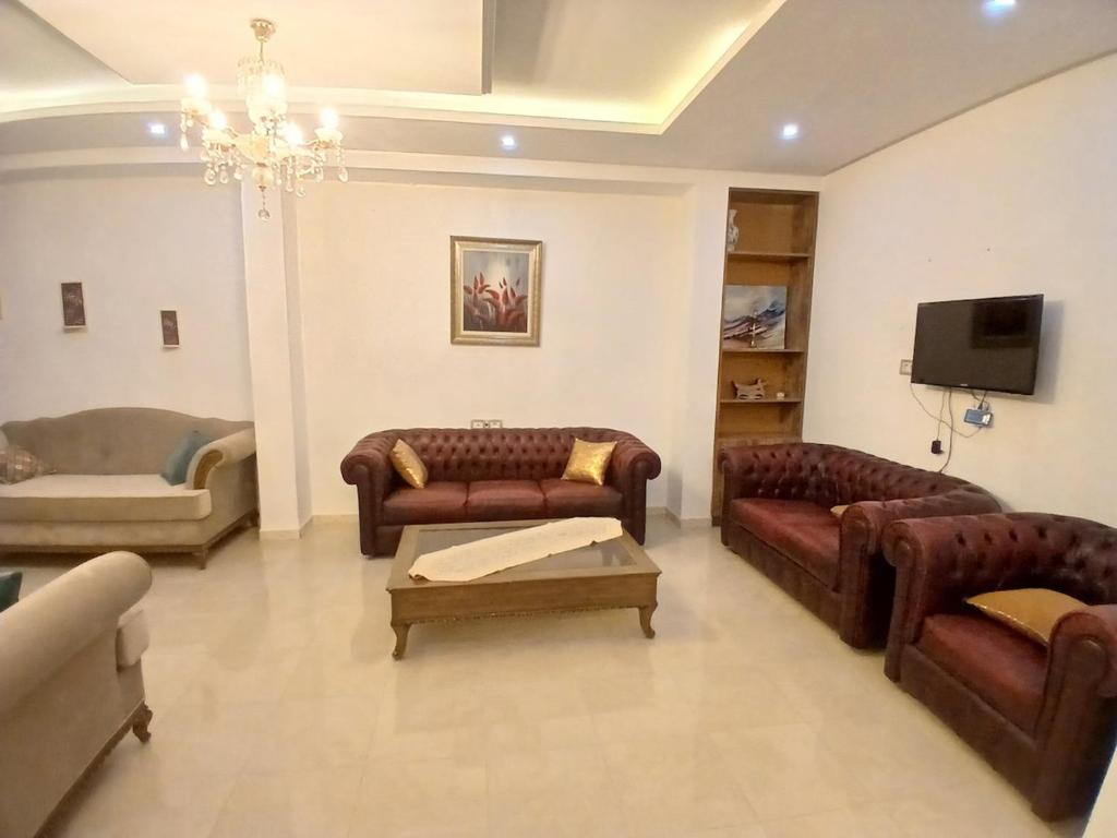 a living room with leather couches and a tv at Hsan Bouslimi in Ez Zahra