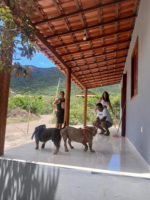 a group of people and two dogs standing under a porch at Casa Cinza Marichi Hospedagem in Vale do Capao
