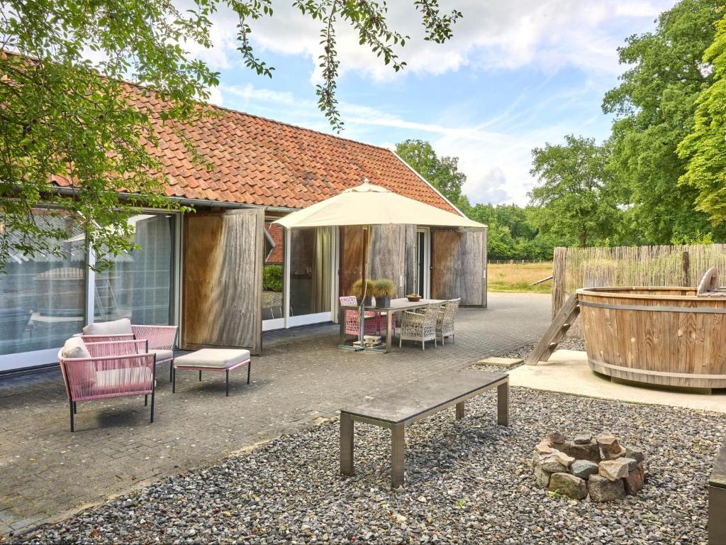 a patio with a bench and an umbrella and a tub at Design Farmers Barn Twente in Haaksbergen
