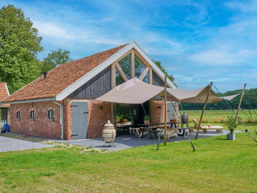 a brick barn with a patio and an umbrella at The Green Wellness Cabin in Haaksbergen