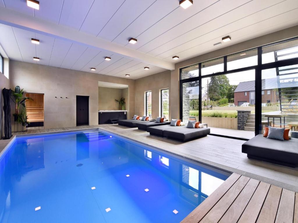 a swimming pool in a house with couches at Villa with Pool & Suites for 12 Guests in Durbuy