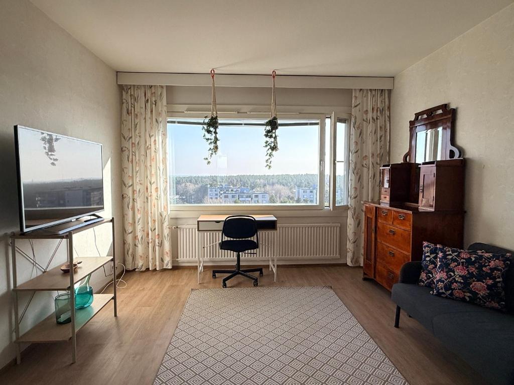 a living room with a desk and a window at The Treetop Apartment in Turku