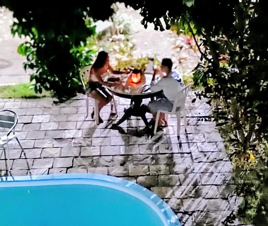 a man and woman sitting at a table near a pool at Só Alegria in Paulista