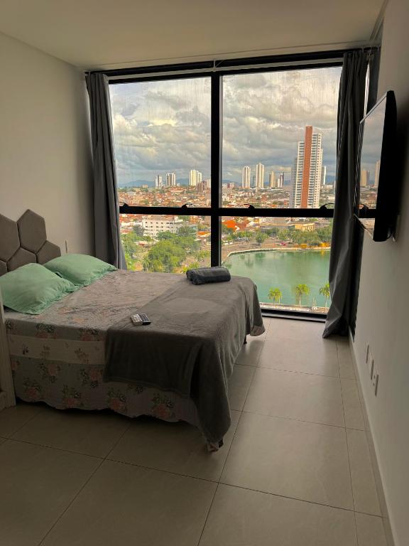 a bedroom with a bed and a large window at Flat luxo vista pro açude in Campina Grande