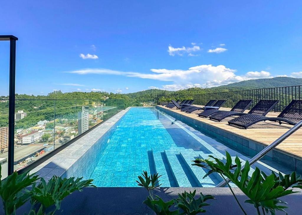 a swimming pool with lounge chairs on a building at ON Smart Lofts - 3 min a pé da Oktoberfest com cama Queen in Blumenau