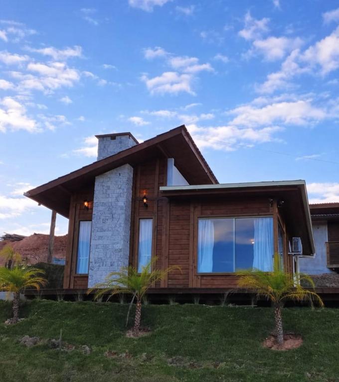 a wooden house with palm trees in front of it at Chalé Recanto do Pimenta 02 in Venda Nova do Imigrante
