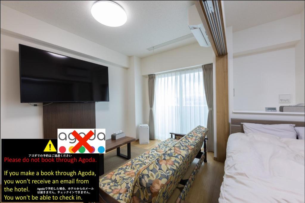 a hotel room with a bed and a flat screen tv at Tomattoco KASUMI in Yamagata