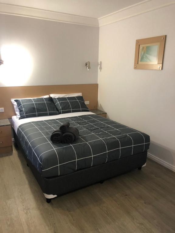 a teddy bear laying on a bed in a bedroom at Latitude20 Cattrall Park Motel in Karratha