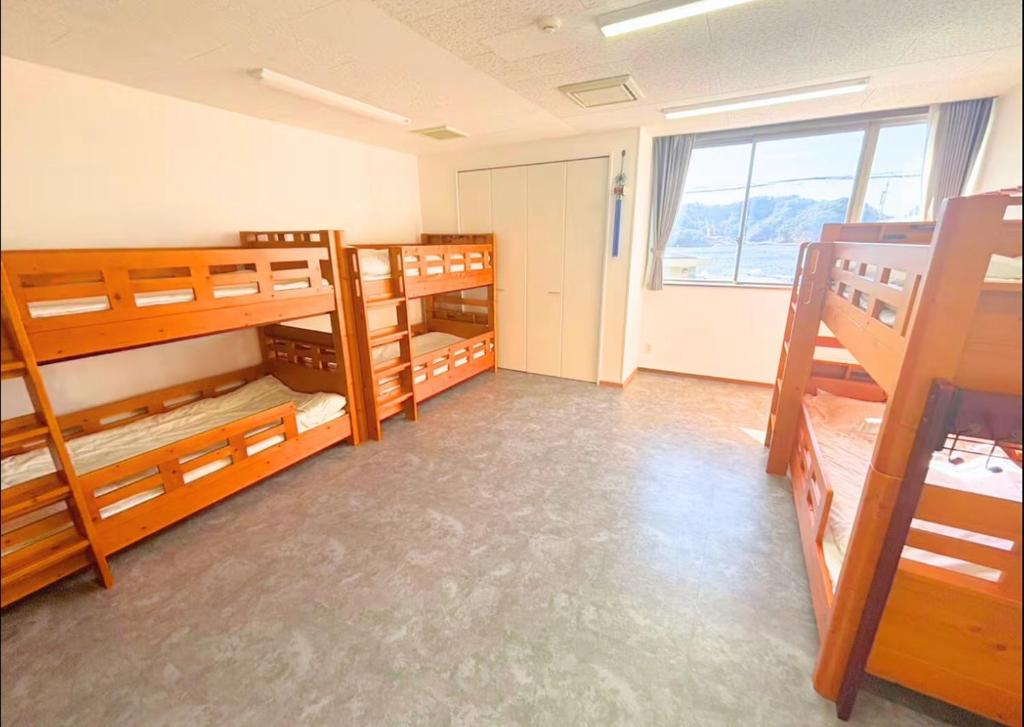 a room with three bunk beds and a window at Magokoro House 203 in Nishiizu