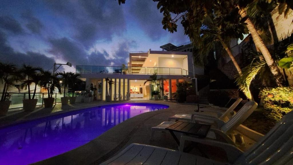 a villa with a swimming pool at night at Villa Casa blanca Con Alberca privada in Acapulco