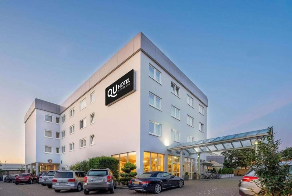 a hotel with cars parked in a parking lot at QU Hotel, Trademark Collection by Wyndham in Augsburg