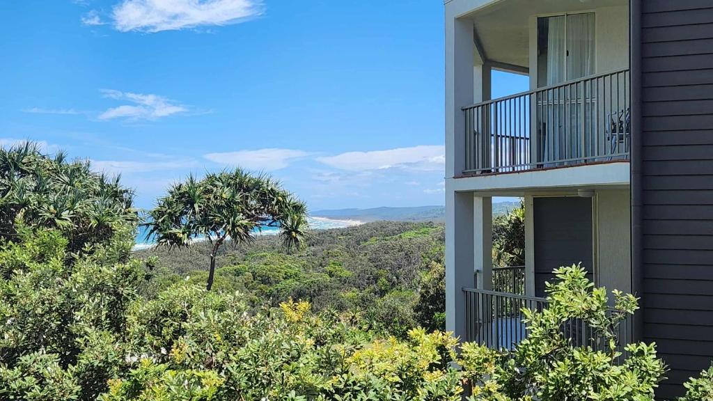 a building with a balcony with a view of trees at Whalewatch Ocean Beach Resort in Point Lookout