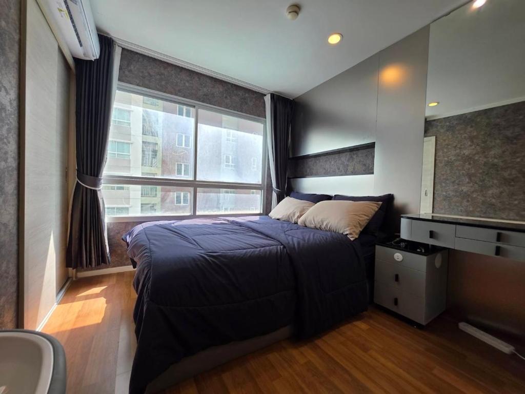 a bedroom with a large bed and a window at Modern Grey in Udon Thani