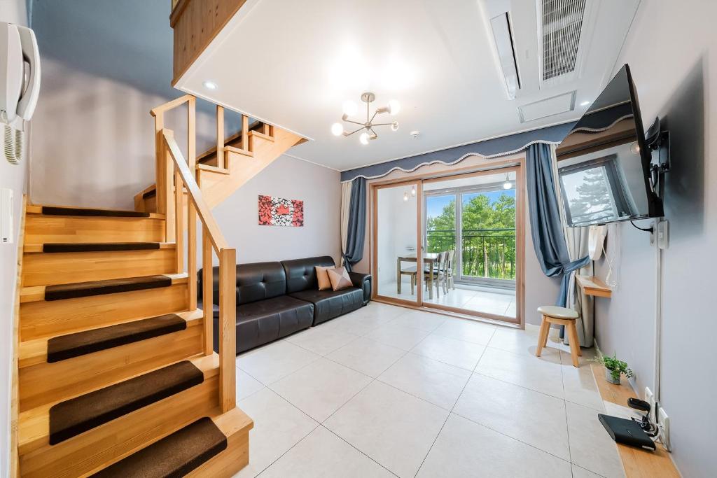 a living room with a staircase and a couch at Samcheok The Ggeullim Pension in Samcheok
