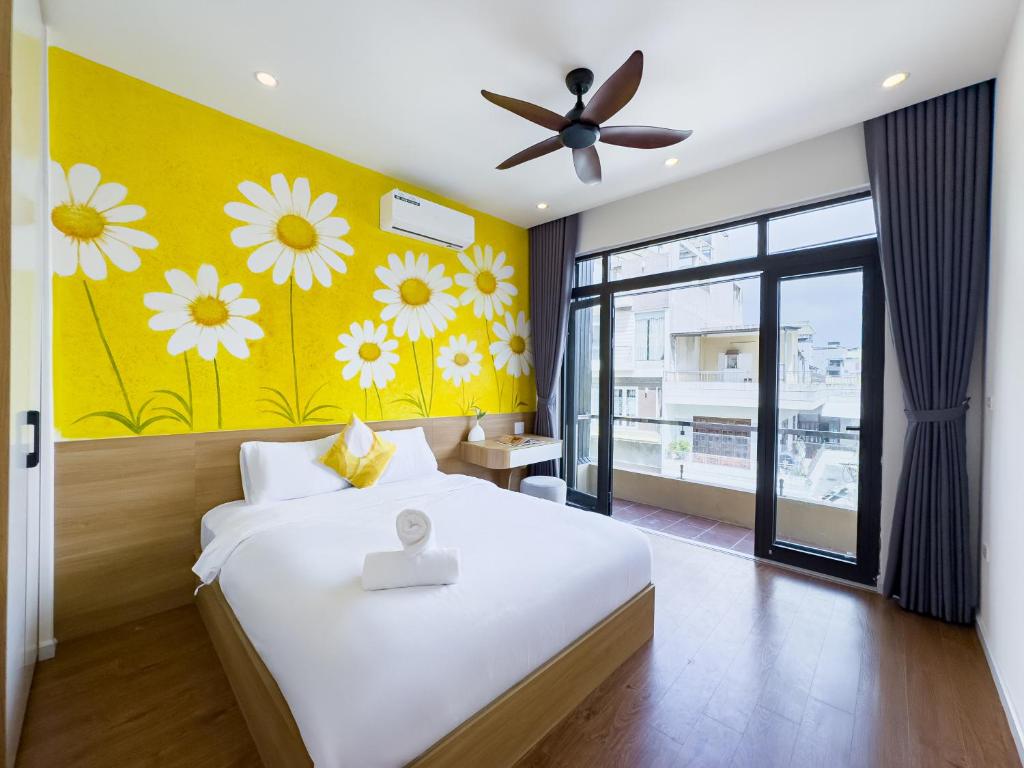 a bedroom with a bed and a yellow wall with flowers at Louis Home in Danang