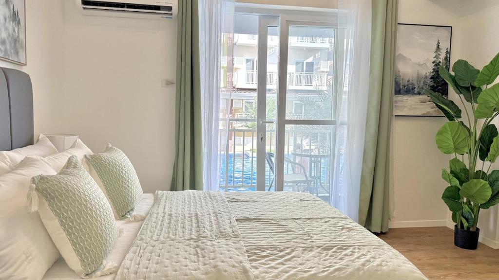 a white bed in a room with a window at Stylish Studio Unit near Airport w Pool and WiFi in Pusok