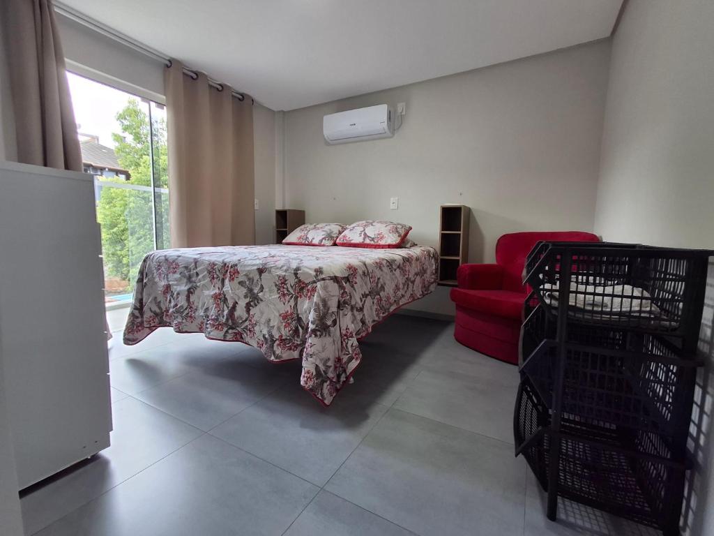 a bedroom with a bed and a red chair at Apartamento novo - 2 Quartos Casal até 4 pessoas - Centro - Santa Rosa - RS in Santa Rosa