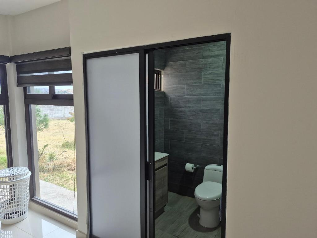 a bathroom with a toilet and a glass door at Finca Sierra Madre in Durango