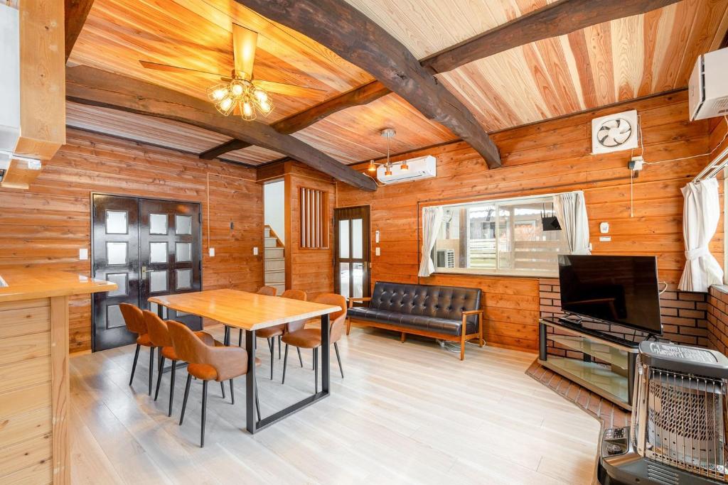 a dining room with a table and a couch at ウッドペッカーC棟BBQPetりんどう湖近くの一棟貸別荘 in Nasu