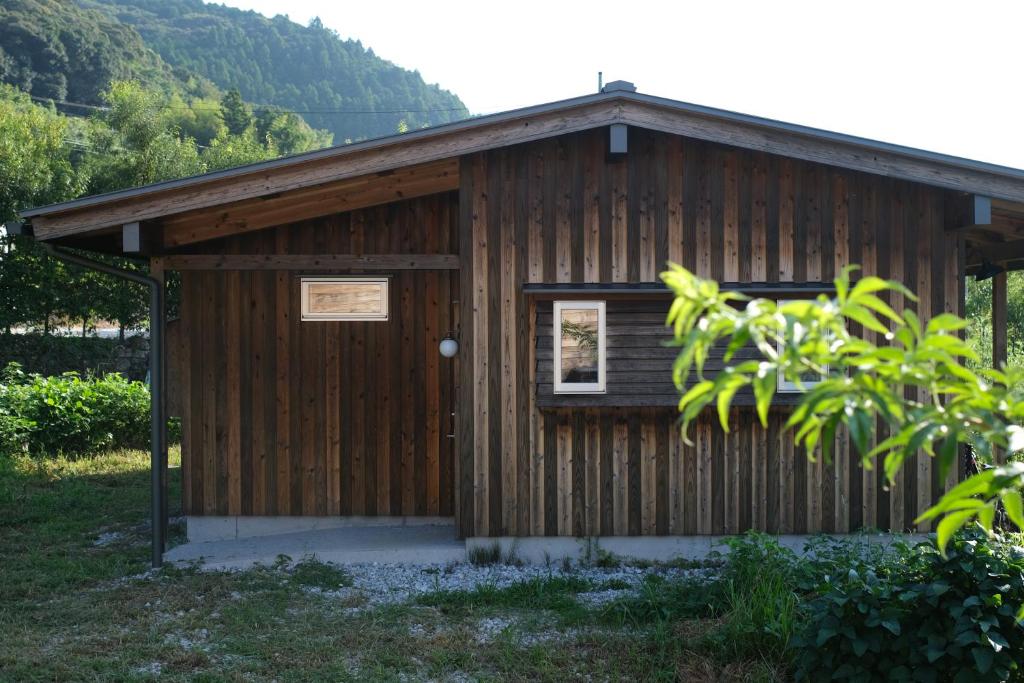a small wooden building with a door and a window at Lotus Retreat ロータスリトリート 高知空港から車で30分 山のふもとの一棟貸しコテージ in Kami