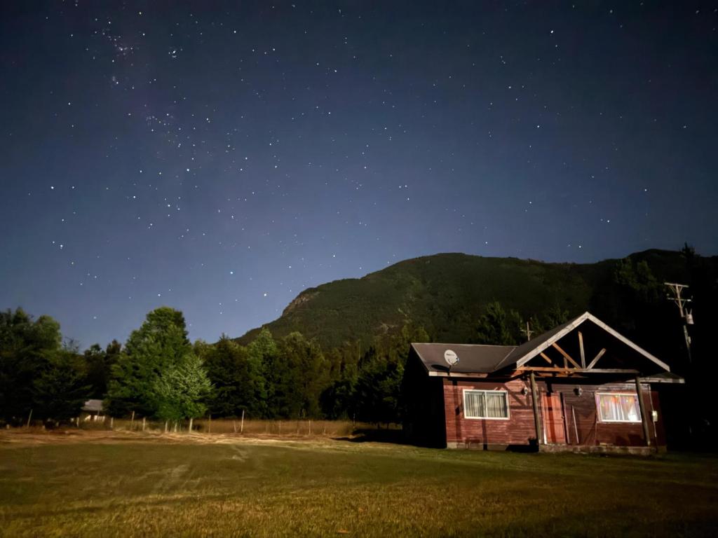 a cabin in a field at night with a starry sky at Cabaña La Ondina in Melipeuco