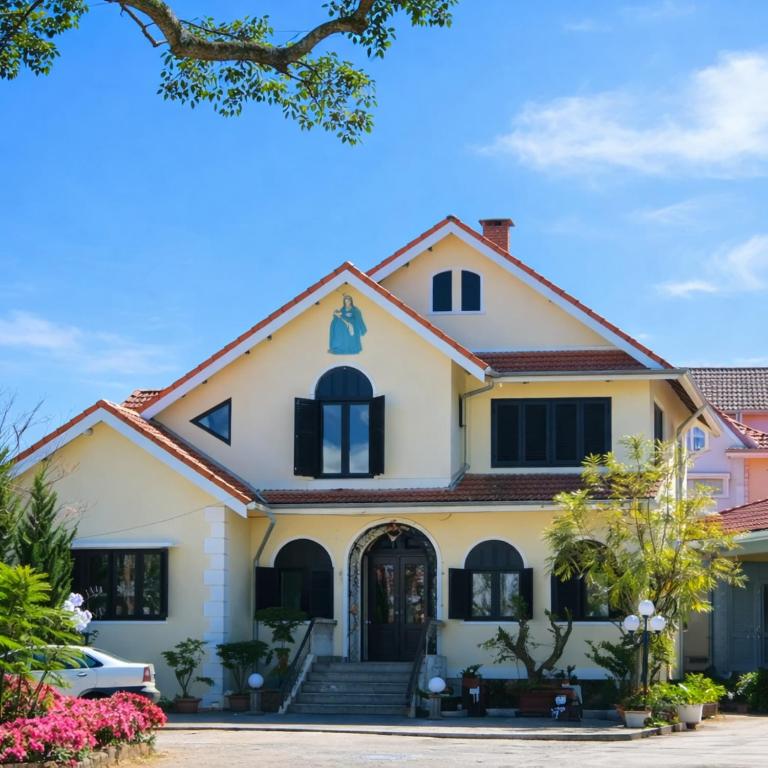 a large white house with black windows at Tomato Villa & Restaurant in Da Lat