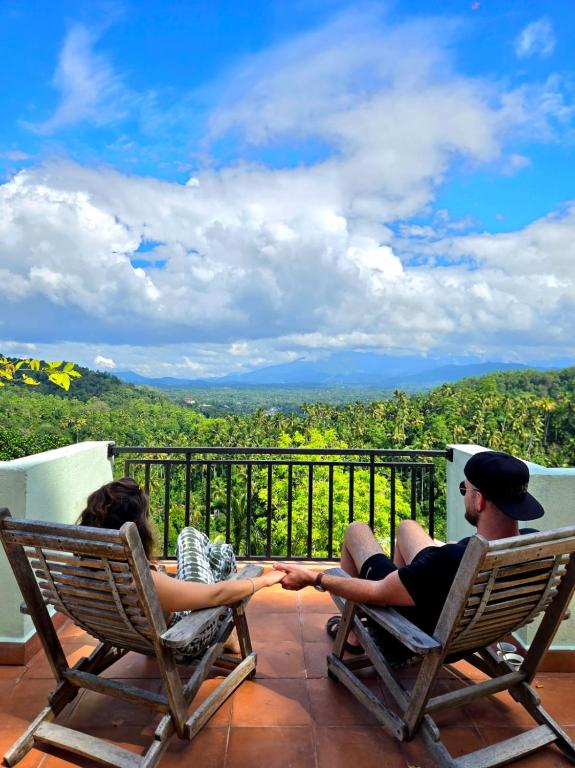 a man and a woman sitting in chairs on a porch at mountain retreat villa in Kandy