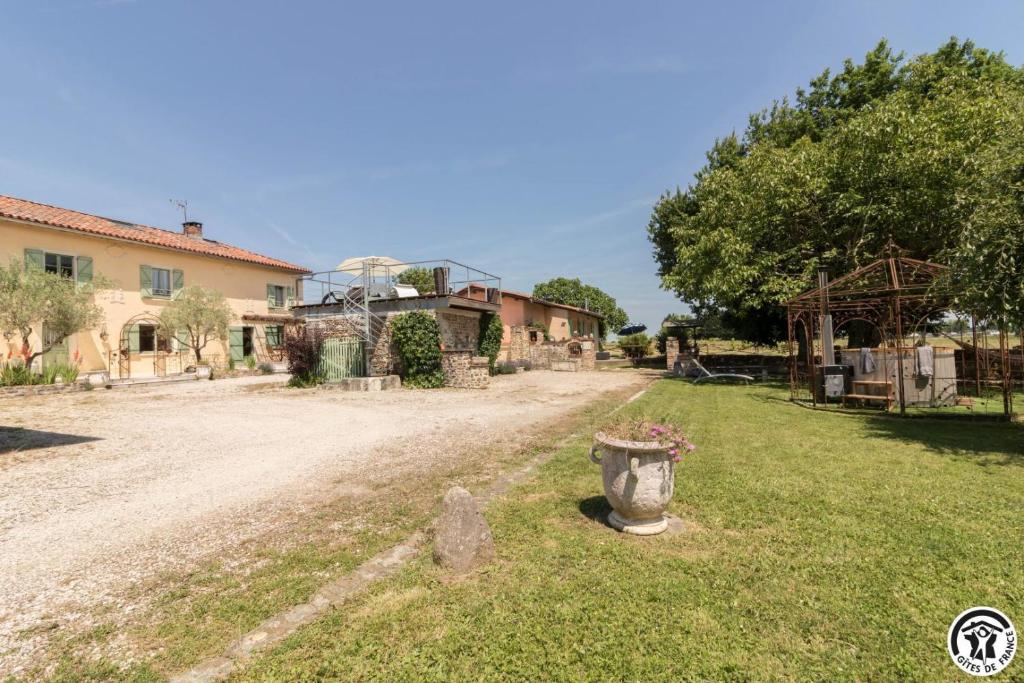 a yard of a house with a vase in the grass at La ferme in Ponlat-Taillebourg
