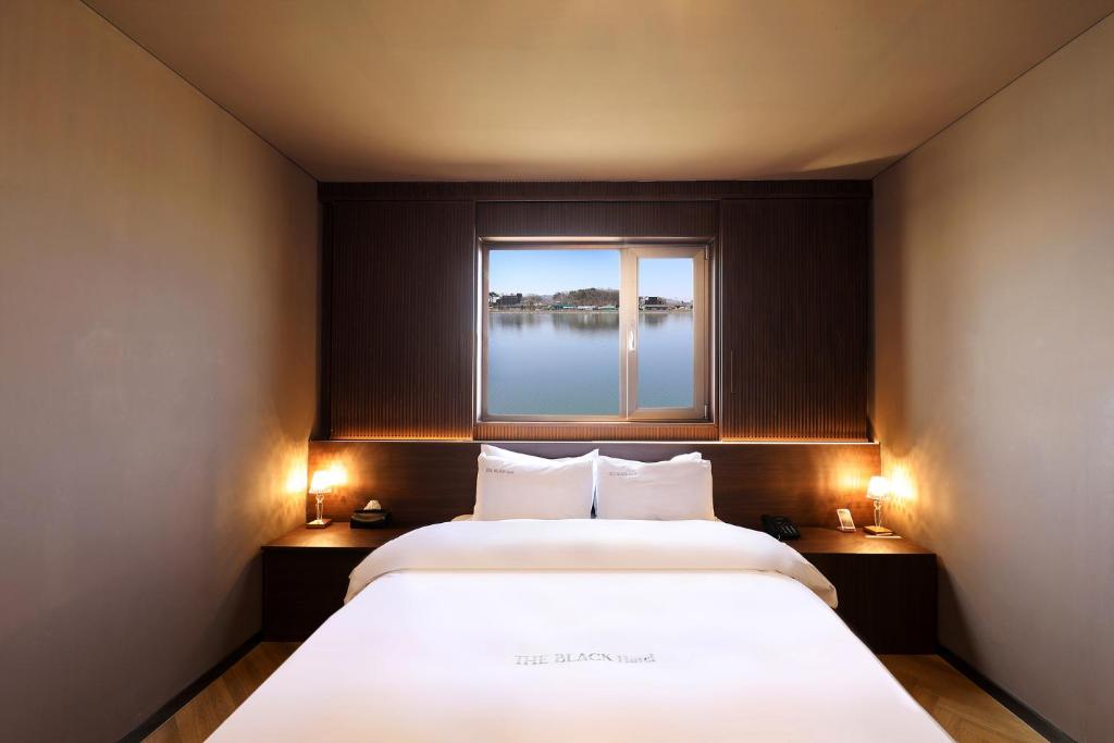 ein Schlafzimmer mit einem großen Bett und einem Fenster in der Unterkunft 호텔 더블랙 in Hwangsan-do