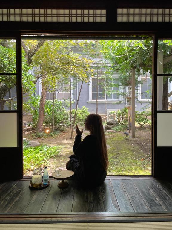 a woman sitting on the floor looking out of a window at Shirafuji in Suzaka