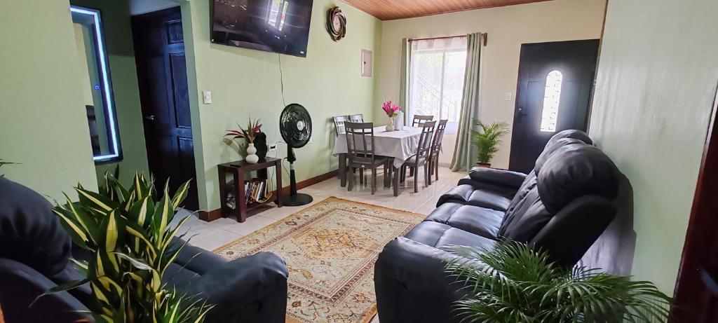 a living room with a leather couch and a table at Arenal Jendrik house in Agua Azul