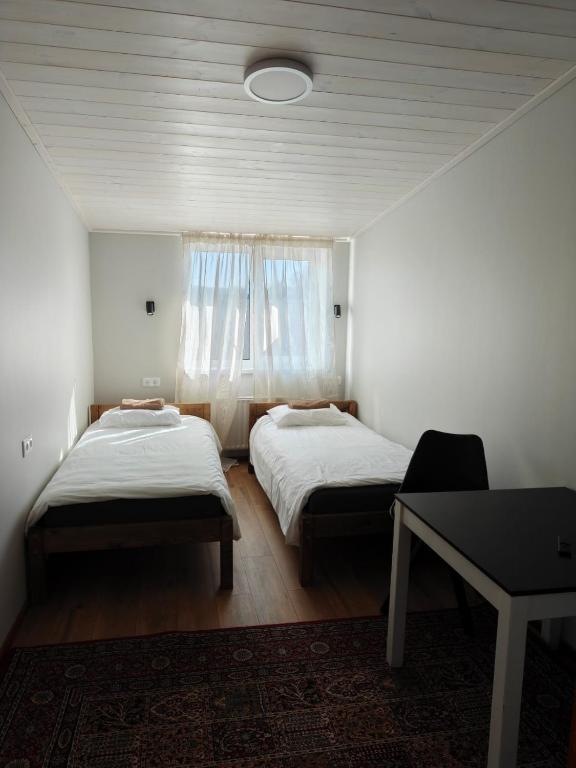 zwei Betten in einem Zimmer mit einem Tisch und einem Fenster in der Unterkunft Tamme in Otepää