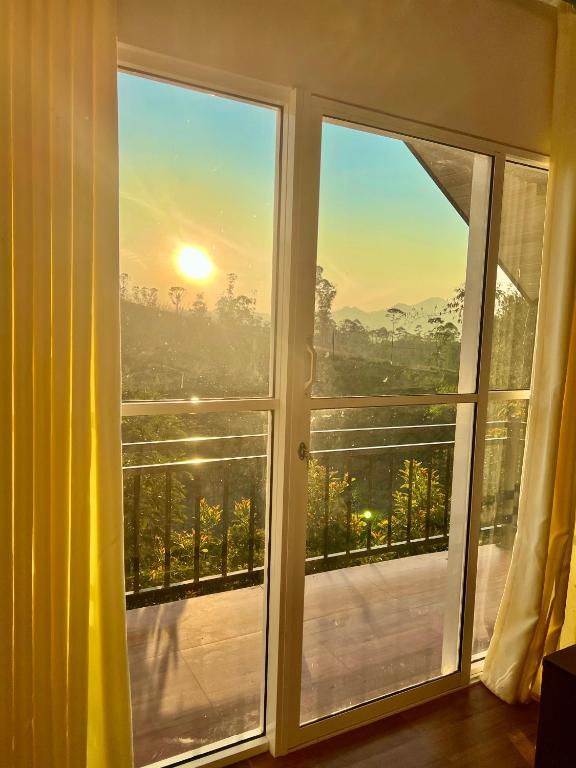 a room with a window with a view of the sunset at Moon Mist Villa in Kotagala