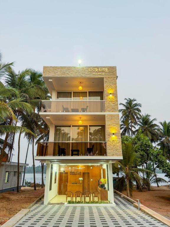a house on the beach with chairs and palm trees at Bella Vista Extended Stay in Kalyānpur