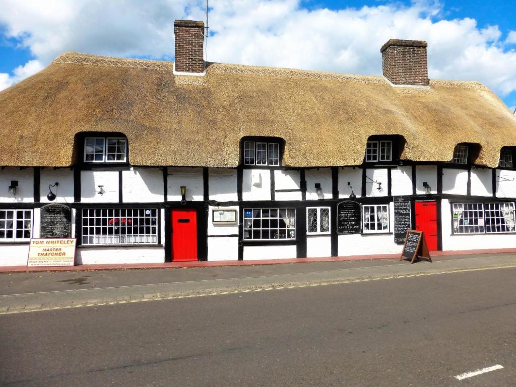 athatched building with red doors and a thatched roof at Avon Accommodation in Ringwood