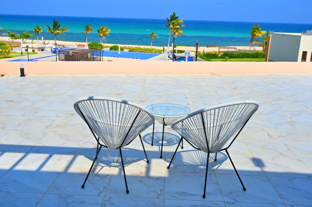 two chairs and a table with a view of the beach at Wateera Jebel Sifah-Beachfront & Golf View in As Sīfah