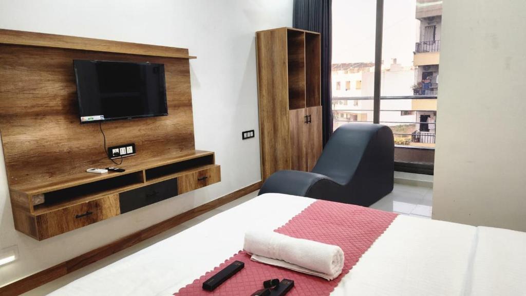 a bedroom with a bed with a chair and a television at Hotel Heritage Prime Junagadh in Junagadh