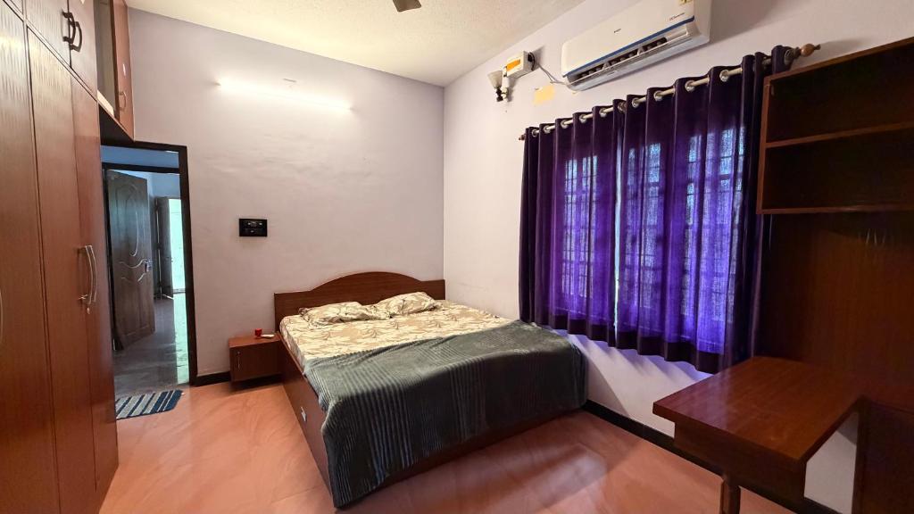 a bedroom with a bed and a window with purple curtains at Zeno Villa Malpe By Beach County in Udupi
