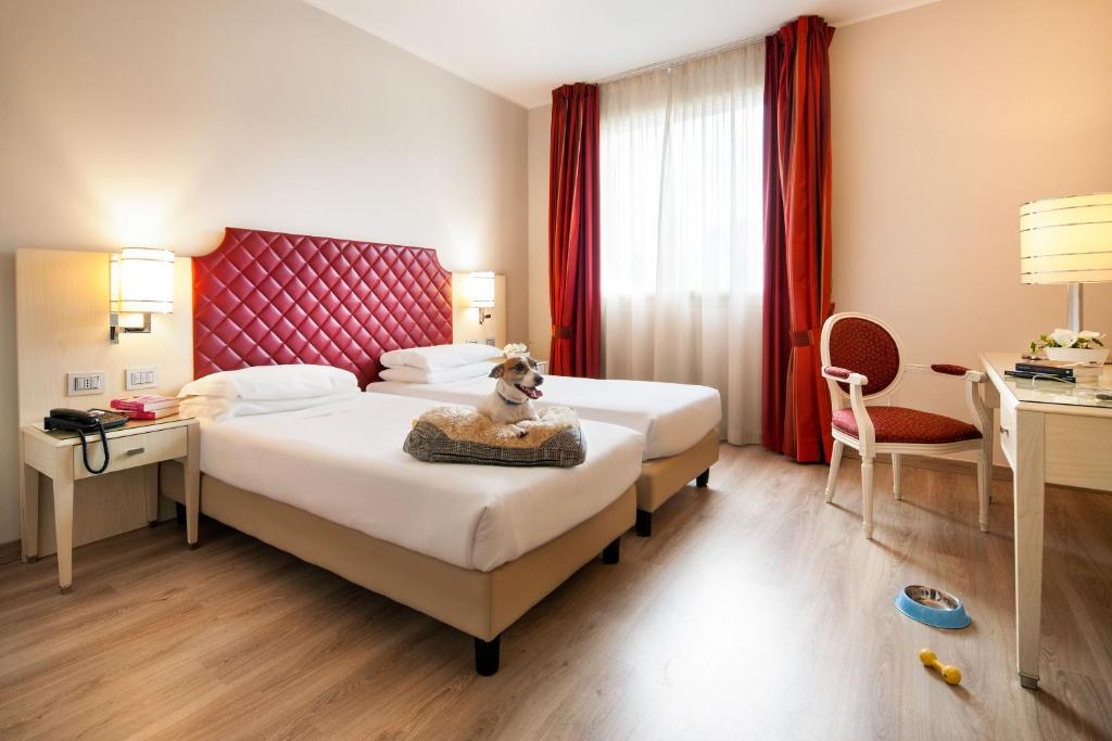 a hotel room with a dog sitting on a bed at Just Hotel Lomazzo Fiera in Lomazzo