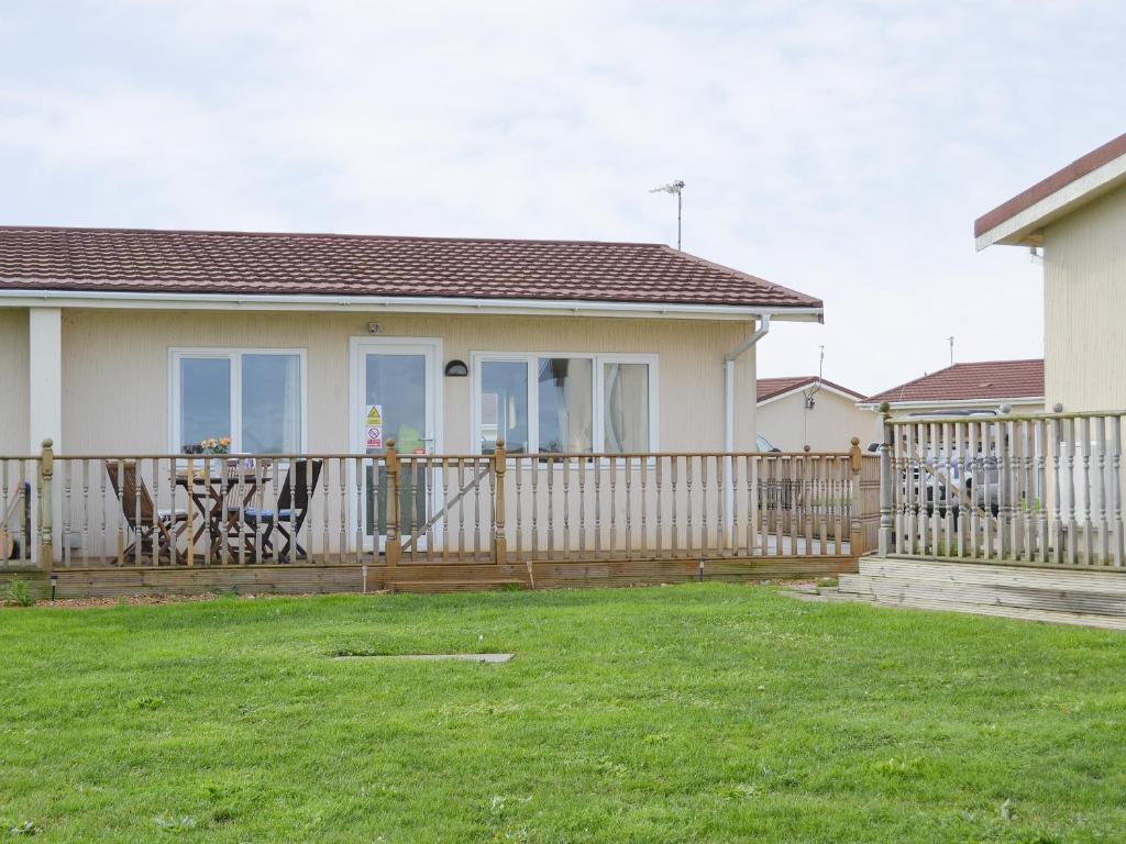 a house with a fence and a table on a deck at Seaspace in Bacton