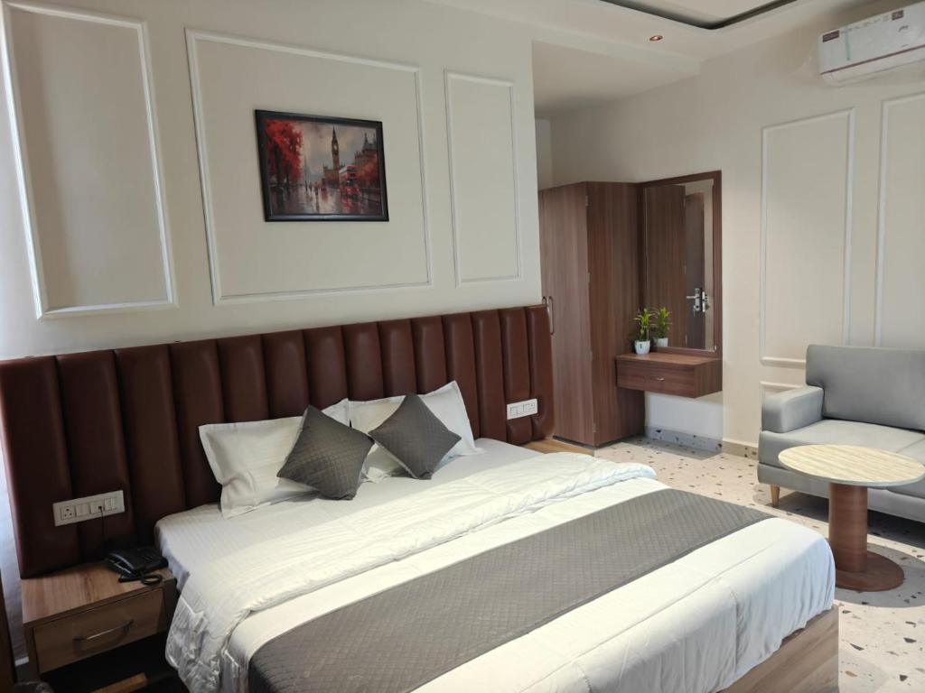 a bedroom with a large bed and a chair at Hotel Natraj Sirsa in Sirsa