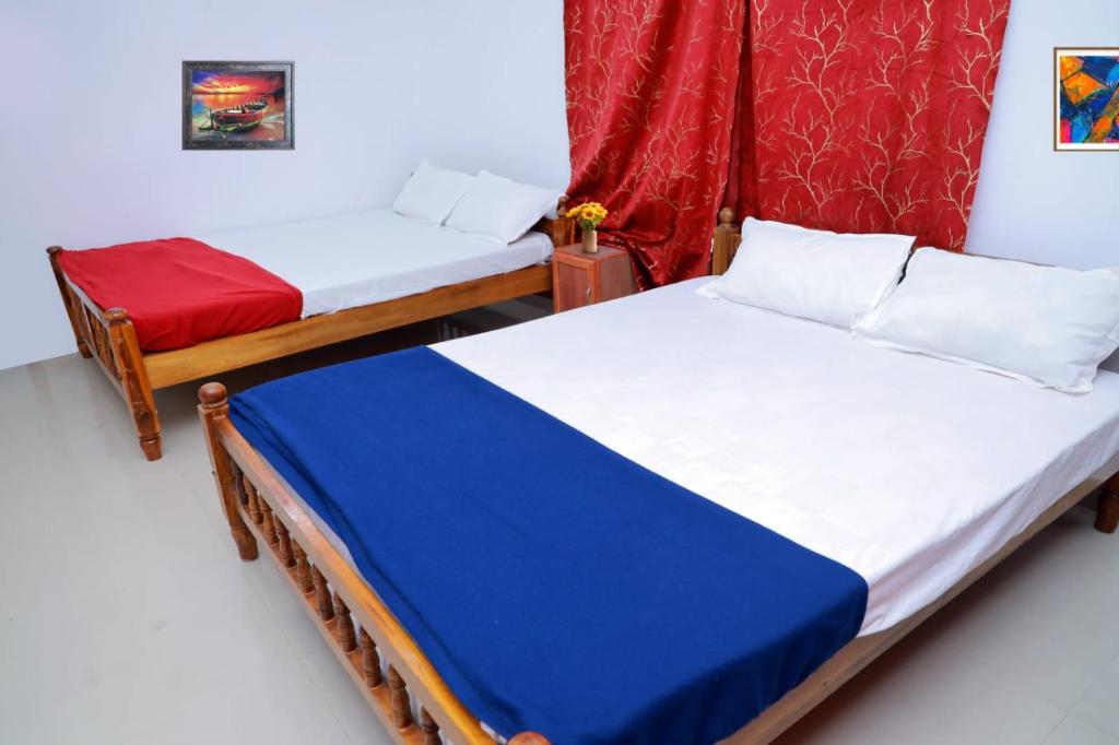 a bedroom with two beds and a red curtain at Sun Shine Resort & Spa in Kovalam