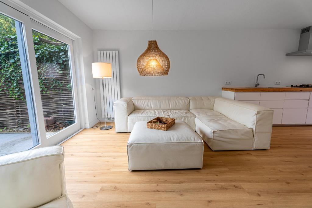 a living room with white furniture and a large window at Spaanse Galeien 13 in Retranchement