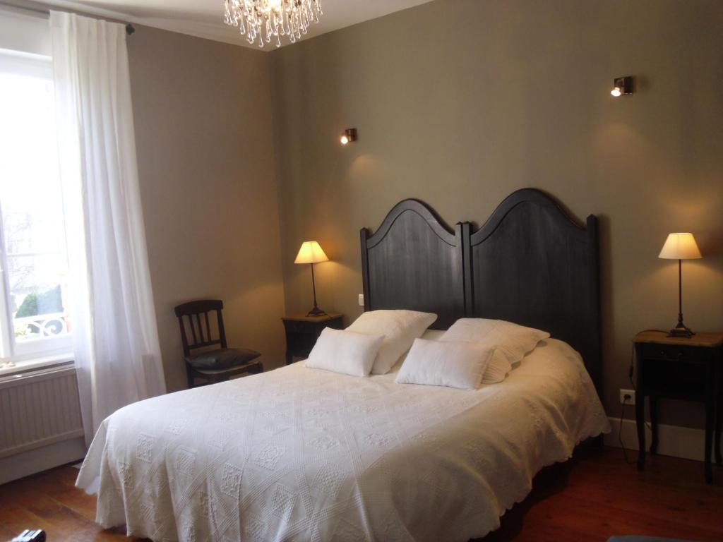 a bedroom with a large bed with white sheets and a chandelier at La Pommeraie in Westrehem