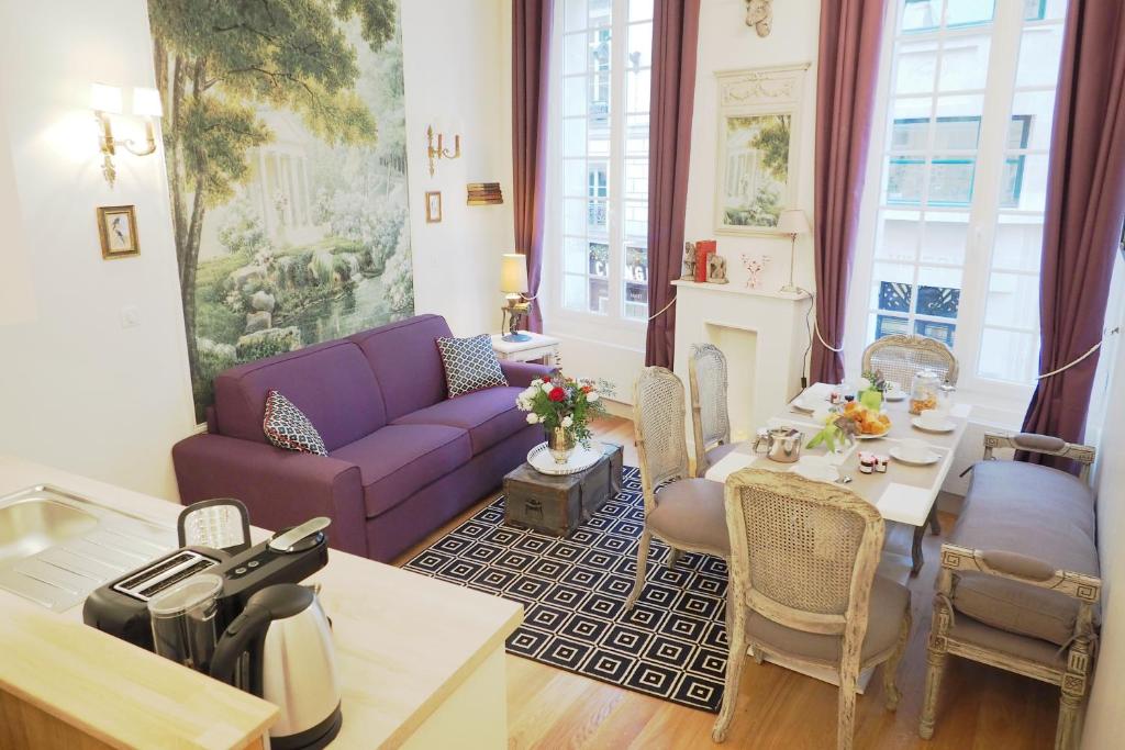 un salon avec un canapé violet et une table dans l'établissement Louvre Opera Private ChicSuites, à Paris