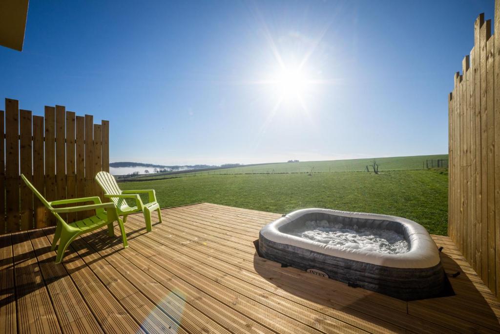 a hot tub on a wooden deck with a chair at Lodge Romy in Schalkendorf