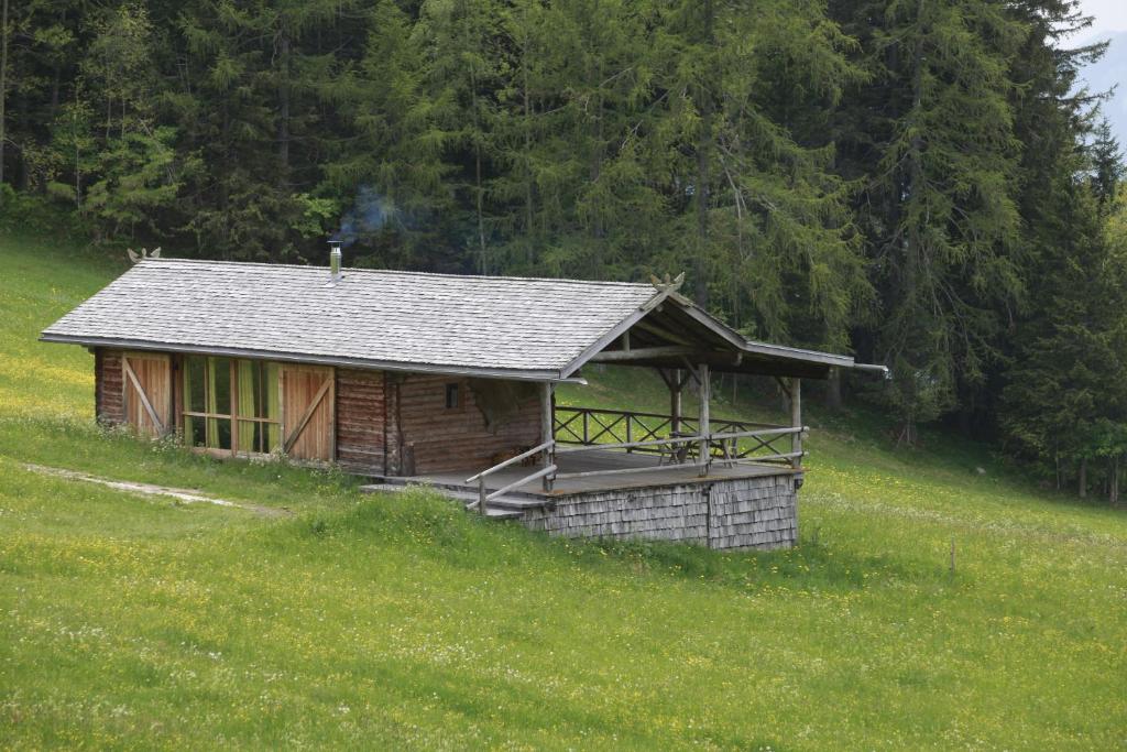 uma pequena cabana numa colina num campo em Berghütte Blockhaus em Redagno