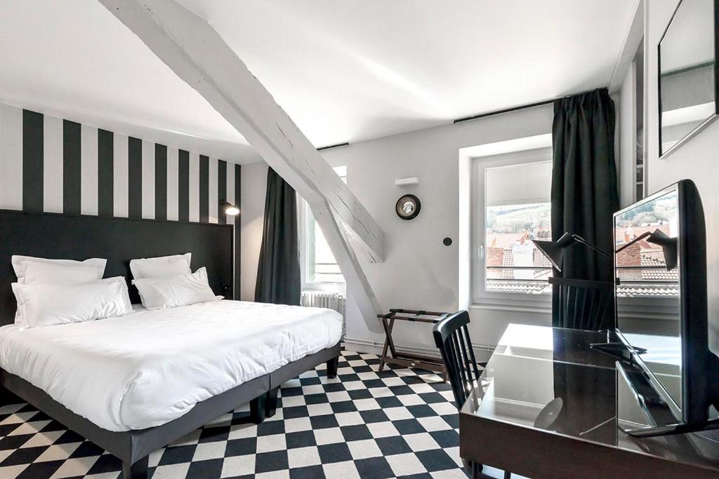 a bedroom with a bed and a desk and a glass table at Hotel des Carmes in Aurillac