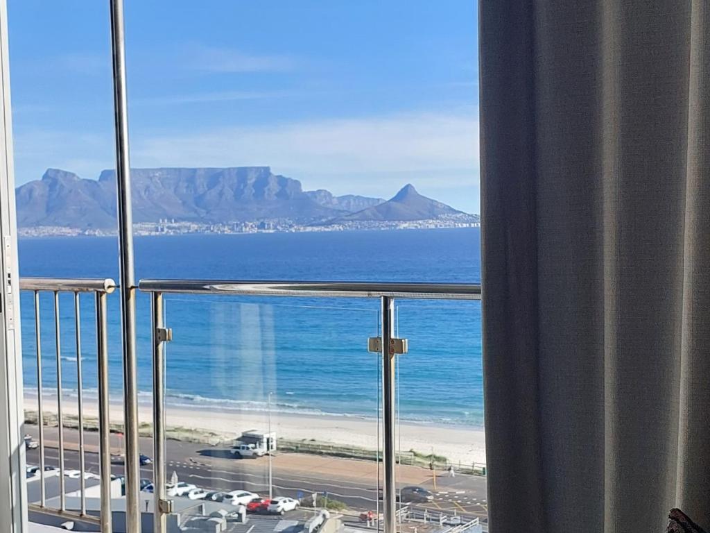 a view of the beach and the ocean from a balcony at Infinity Beachfront 607, Blouberg Beach, Cape Town in Bloubergstrand