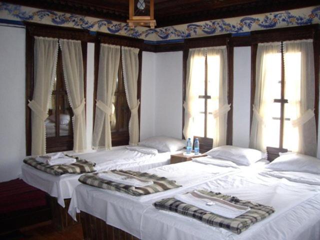 two beds in a bedroom with white sheets and windows at Popsokol House in Bratsigovo